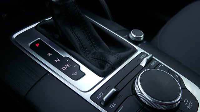 The driver moves the silver black gearshift of a luxurious car - closeup