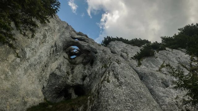 Looking up to the white moving clouds over the high cliifs in  Piatra Craiului Mountains, Romania. 4k timelapse.