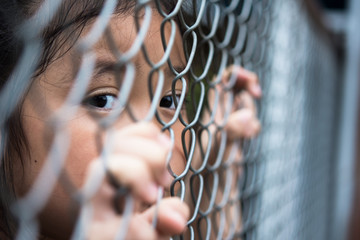 Little girl with metal fence, feeling no freedom.