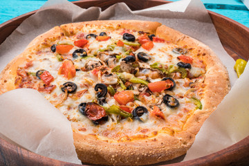 Vegetarian pizza with vegetables on blue table.