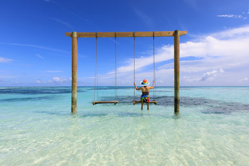 Women on swings in the sea., Maldives island