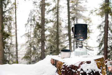 preparing food with a portable gas burner in a winter forest. Bushcraft, hunting and hiking concept