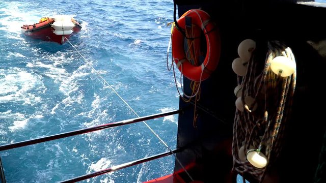 The ship pulls a boat on the sea