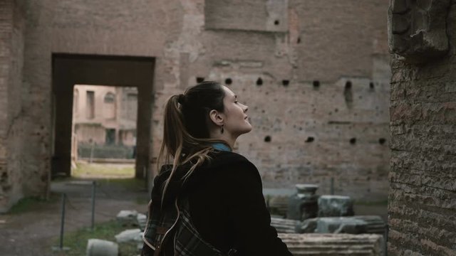 Tourist walking in Rome, Italy, learning about ancient history. Woman touching the brick wall of antique castle columns.