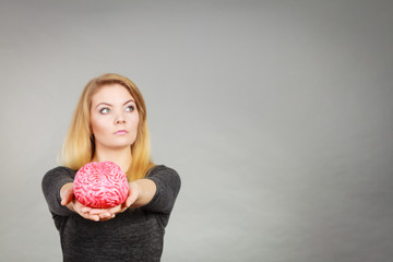 Woman thinking and holding fake brain