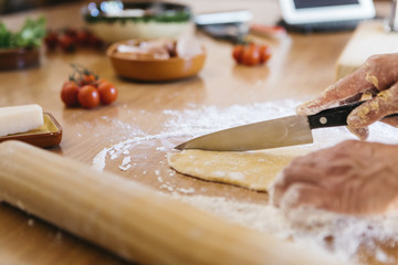 Fototapeta na wymiar Hands cutting dough for fresh ravioli