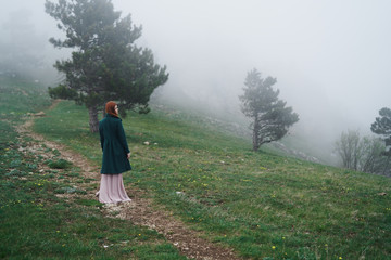 Beautiful young woman in a long dress in the mountains