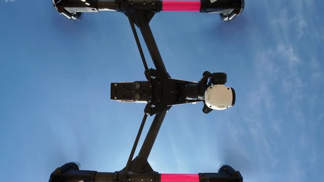 4k drone video, view from below into blue sky while quadcopter is taking off and moving up
