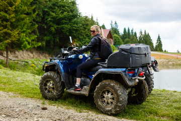 Fototapeta na wymiar Excited young woman on quad bike. Happy young woman driving all terrain vehicle in nature.