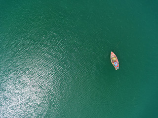 Obraz premium Fishing boat floating in the sea. The beautiful bright blue water in a clear day.