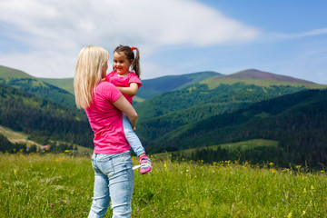 Mother and little daughter are playing in the mountains