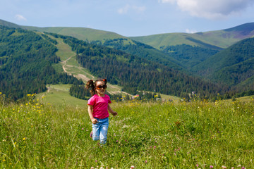 Naklejka na ściany i meble funny little happy girl on the mountain top. Freedom, little girl playing on meadow. Travel, lifestyle concept