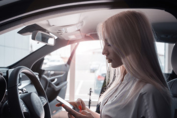 Girl in the car with a mobile/ A chic blonde at the wheel of an expensive car with a mobile phone.