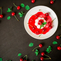 Delicious Panna cotta with cherry in white plate on a dark table, tasty Italian dessert. Flat lay,...