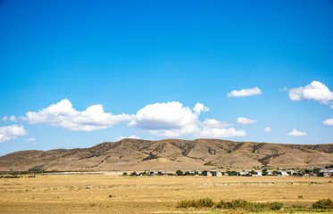 Desert landscape. Blue sky with white clouds. Summer steppe landscape. Hot desert with mountains view.