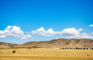 Desert landscape. Blue sky with white clouds. Summer steppe landscape. Hot desert with mountains view.