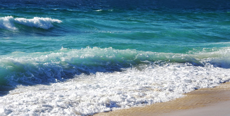 waves crash over the beach at Algarve, Portugal