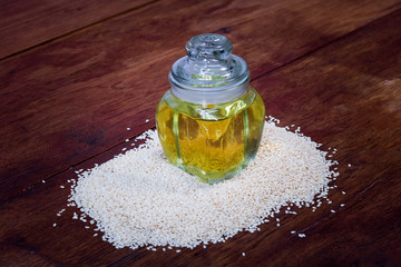 sesame seeds and sesame oil in a bottle on a wooden table