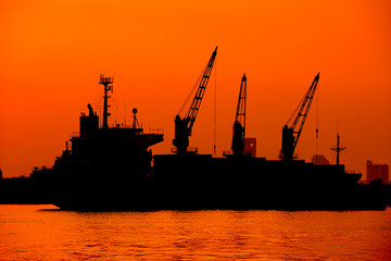 Fototapeta premium container ship in import export and business logistic.By crane , Trade Port , Shipping.Tugboat assisting cargo to harbor.Aerial view. Top view.Silhouette.