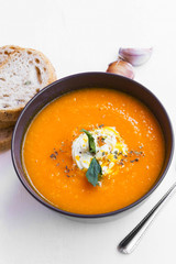 Creamy carrot soup with cream sauce on top, rustic vegetable soup in a bowl
