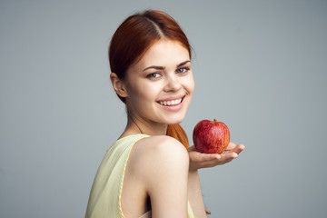 Beautiful young woman on a gray background holding an apple