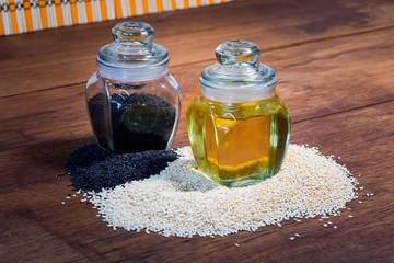 sesame seeds and sesame oil in a bottle on a wooden table