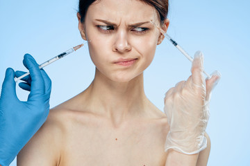 1157187 Beautiful young woman on a blue background holds a syringe, medicine, plastic