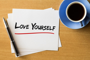 Love yourself - handwriting on papers with cup of coffee and pen, love concept