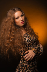 Girl in leopard dress and black shoes on brown background