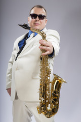 Fototapeta premium And you play. Saxophonist. Caucasian man with a saxophone. Dressed in a white suit. The studio silhouette on a white background.