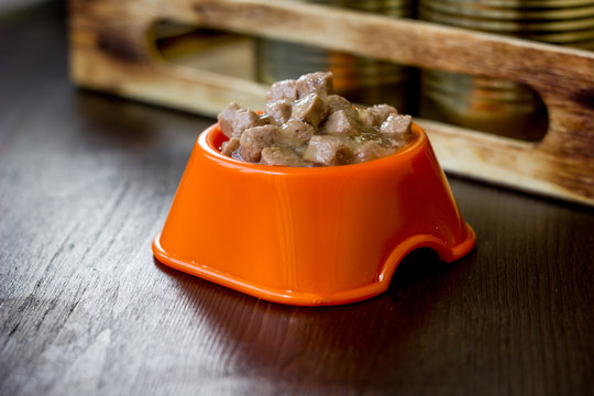 Canned pet food in a orange plastic bowl.