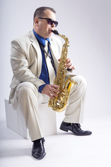 Fototapeta premium Saxophone only. Saxophonist. Caucasian man with a saxophone. Dressed in a white suit. The studio silhouette on a white background.