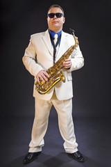 Fototapeta premium Saxophonist playing saxophone. The soloist, saxophonist plays the saxophone. Dressed in a suit. Man.