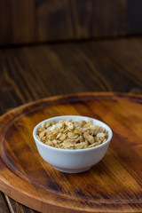 Granola or muesli in white ceramic bowl over wooden table.