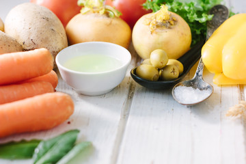 Vegetables, olives and spices over white wooden table.