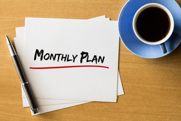 Monthly plan - handwriting on papers with cup of coffee and pen, business concept