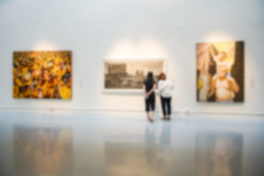 Blurry background of art gallery with people pay attention with the image on the wall.