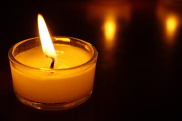 Candles light flame on low light background.