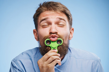 Young guy with a beard on a blue background holds a spinner
