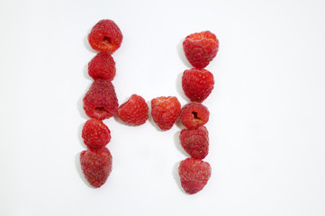 Alphabetical letter H made of raspberries on a white background