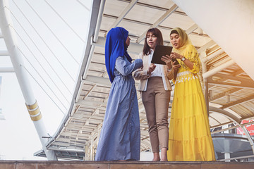 Muslim women messaging on a tablet in the city.