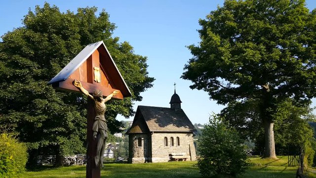 Little Chapel and Jesus statue on hill at sunrise in Monschau