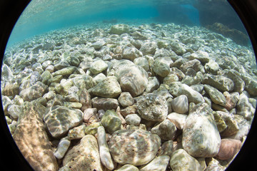 Pebble beach with azure sea water.Fisheye lens uses to take a special effect.