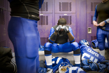A football player sitting in a thoughtful state inside locker room