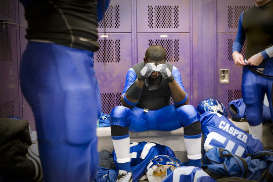 A football player sitting in a thoughtful state inside locker room