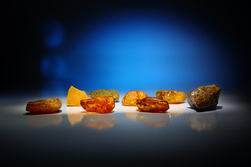 Amber. Amber pieces on a beautiful blue background. Several pieces of fossil mineral from resin of different color and shape. Sun stone on a beautiful luxury background.