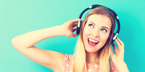 Fototapeta premium Happy young woman with headphone on pink background