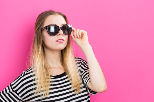 Young woman with sunglasses on a pink background
