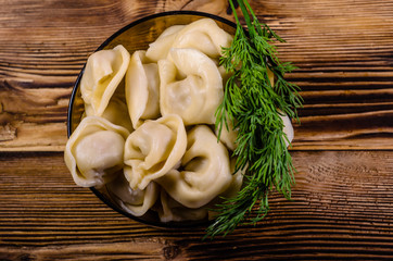 Fresh dumplings in glass bowl on wooden table. Top view