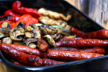 Grilled sausages, chicken breasts, edible mushrooms, zucchini and red pepper in a pan. Selective focus. 